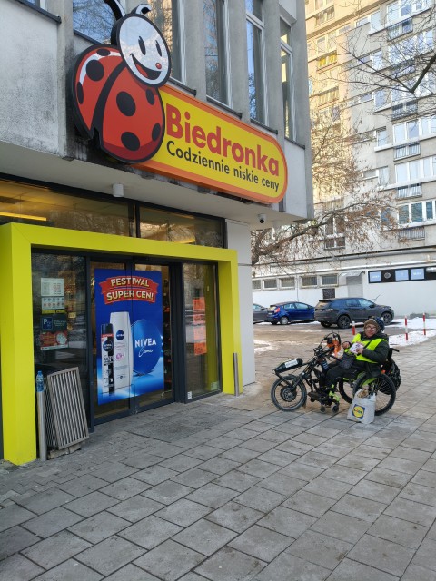 Zdjęcie do wpisu: Zbiórka dla Zbyszka w centrum Warszawy, mimo zimna na dworze. ❄️  Do Biedronki nie było możliwości wejścia od razu do środka – musiałem prowadzić zbiórkę przy stojaku na zewnątrz.